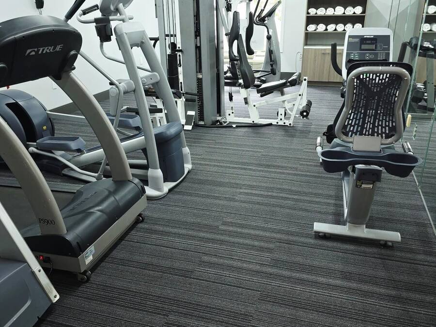 A gym with treadmills, weight machines, and a mirrored wall.