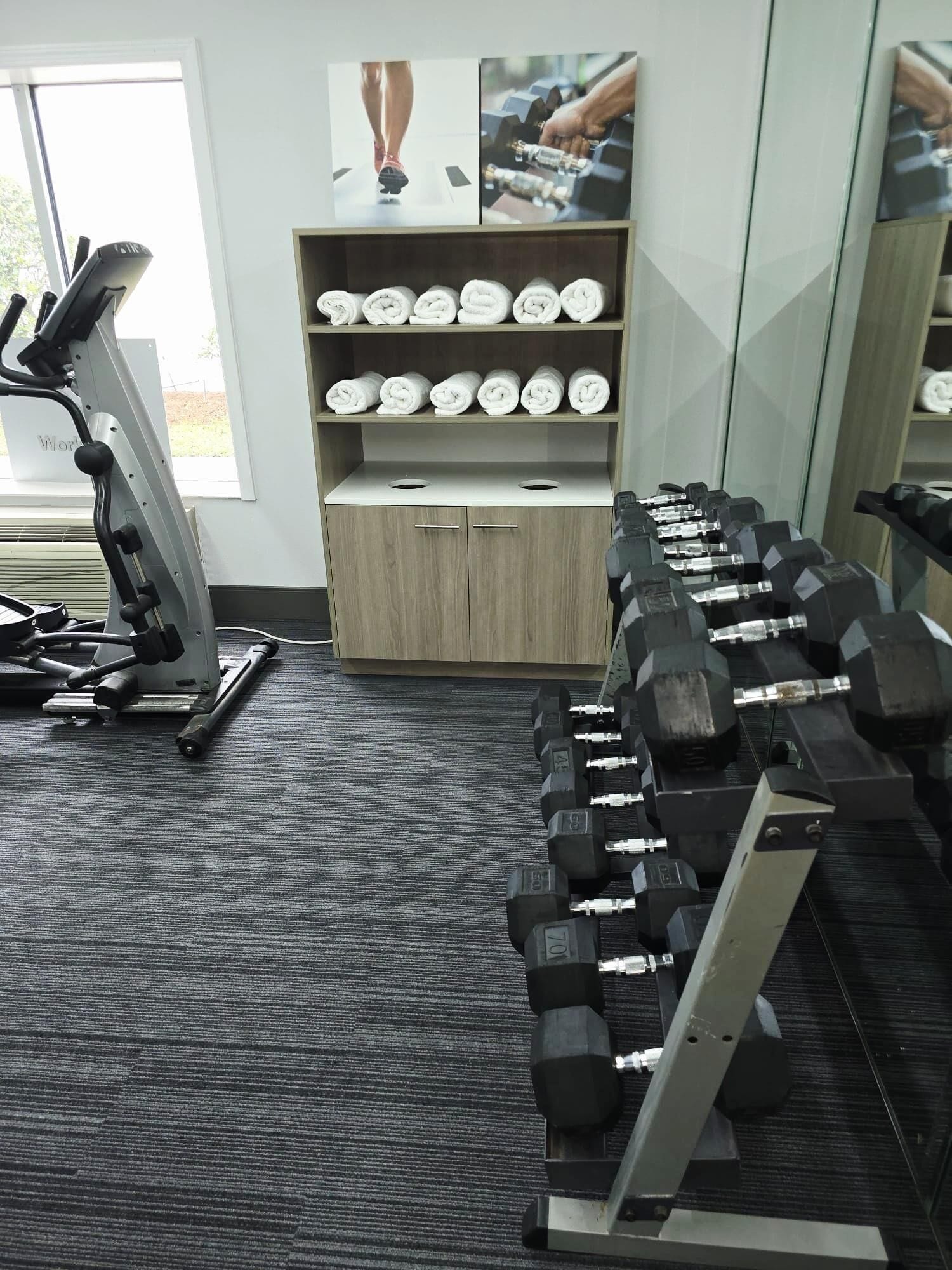 A gym with exercise equipment, including a treadmill, dumbbells, and a bench press.