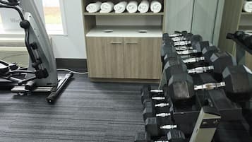 A gym with exercise equipment, including a treadmill, dumbbells, and a bench press.