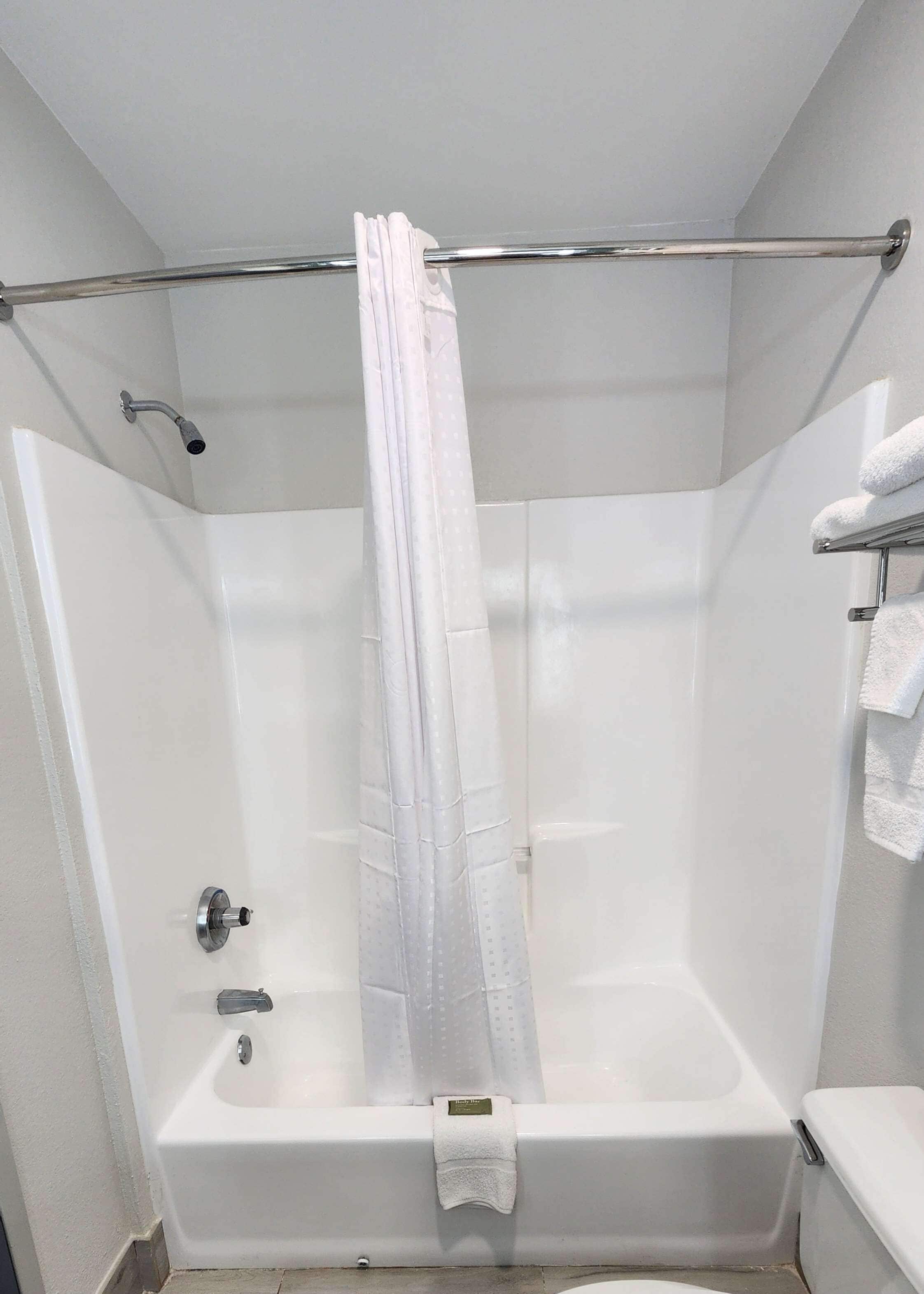 A white bathroom with a bathtub, a shower curtain, and a towel rack.