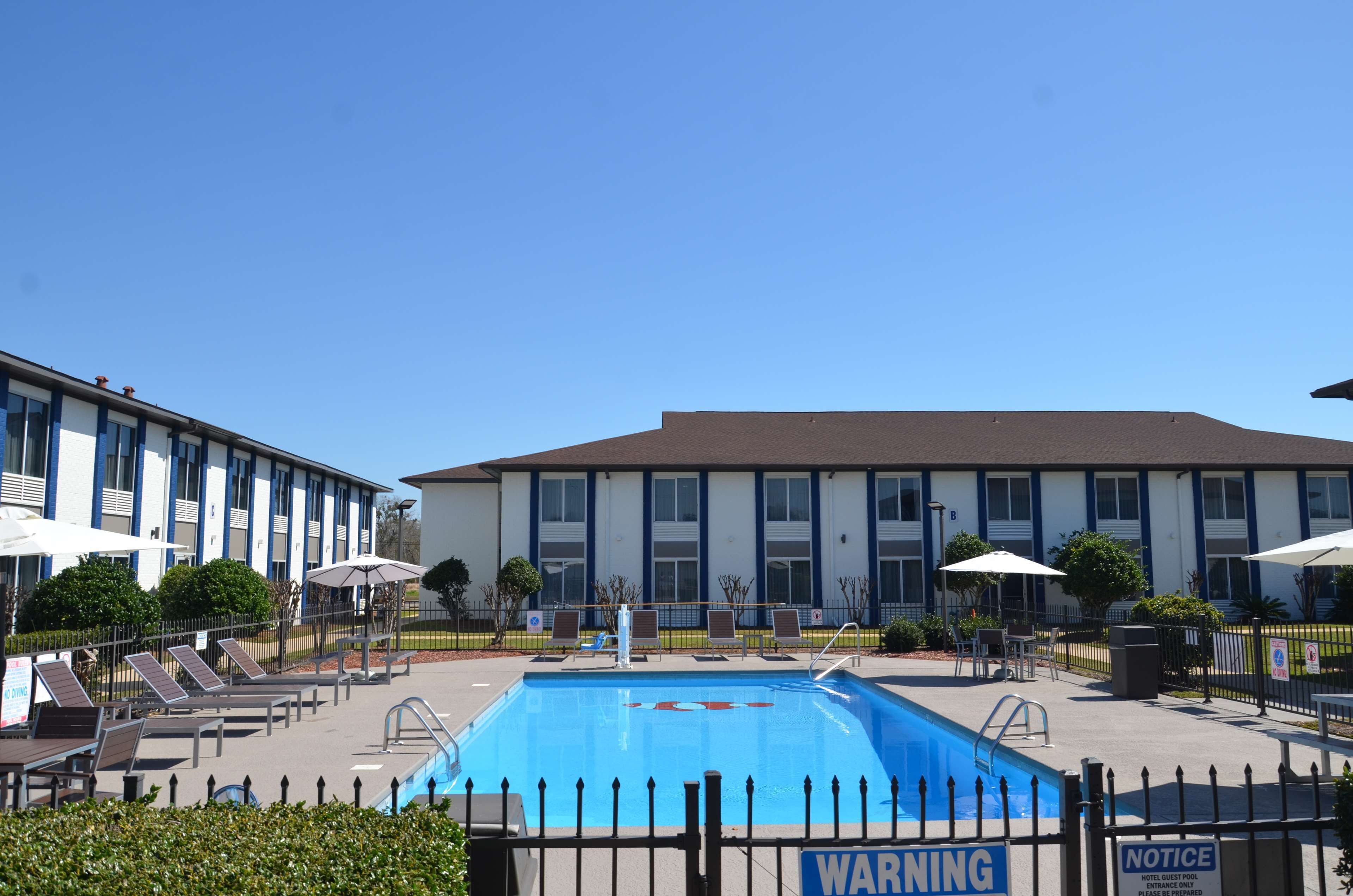 A hotel with a swimming pool, sun loungers, and umbrellas.