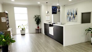 A reception area with a reception desk, a clock, a TV, and a sign for AMERICAS BEST VALUE INN & SUITES.