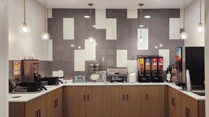 A modern coffee shop with a counter, coffee machines, and vending machines.