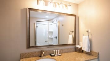Une salle de bain avec un grand miroir, un lavabo et une douche.