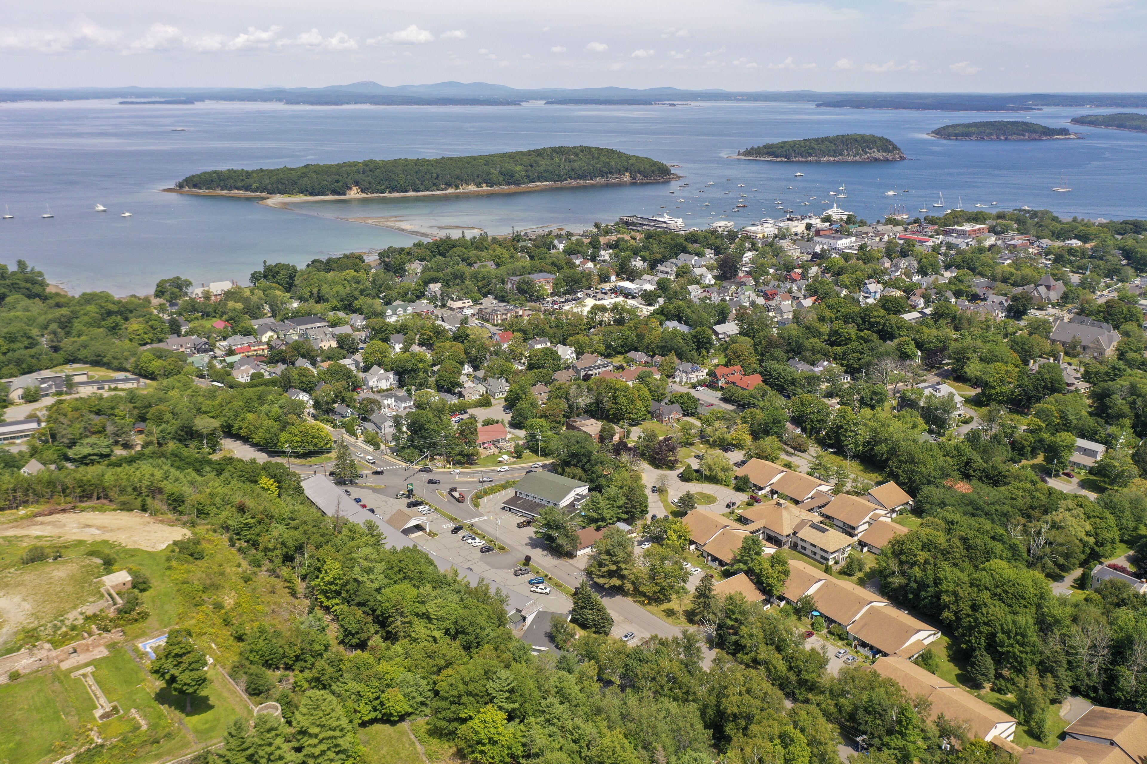 Ilmakuva rannikkokaupungista, jossa näkyvät asuinalueet, vierasvenesatama ja taustalla olevat saaret.
