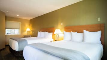 A hotel room with two beds, a window with blinds, and two bedside lamps.