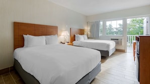A hotel room with two beds, a balcony, and a kitchenette.