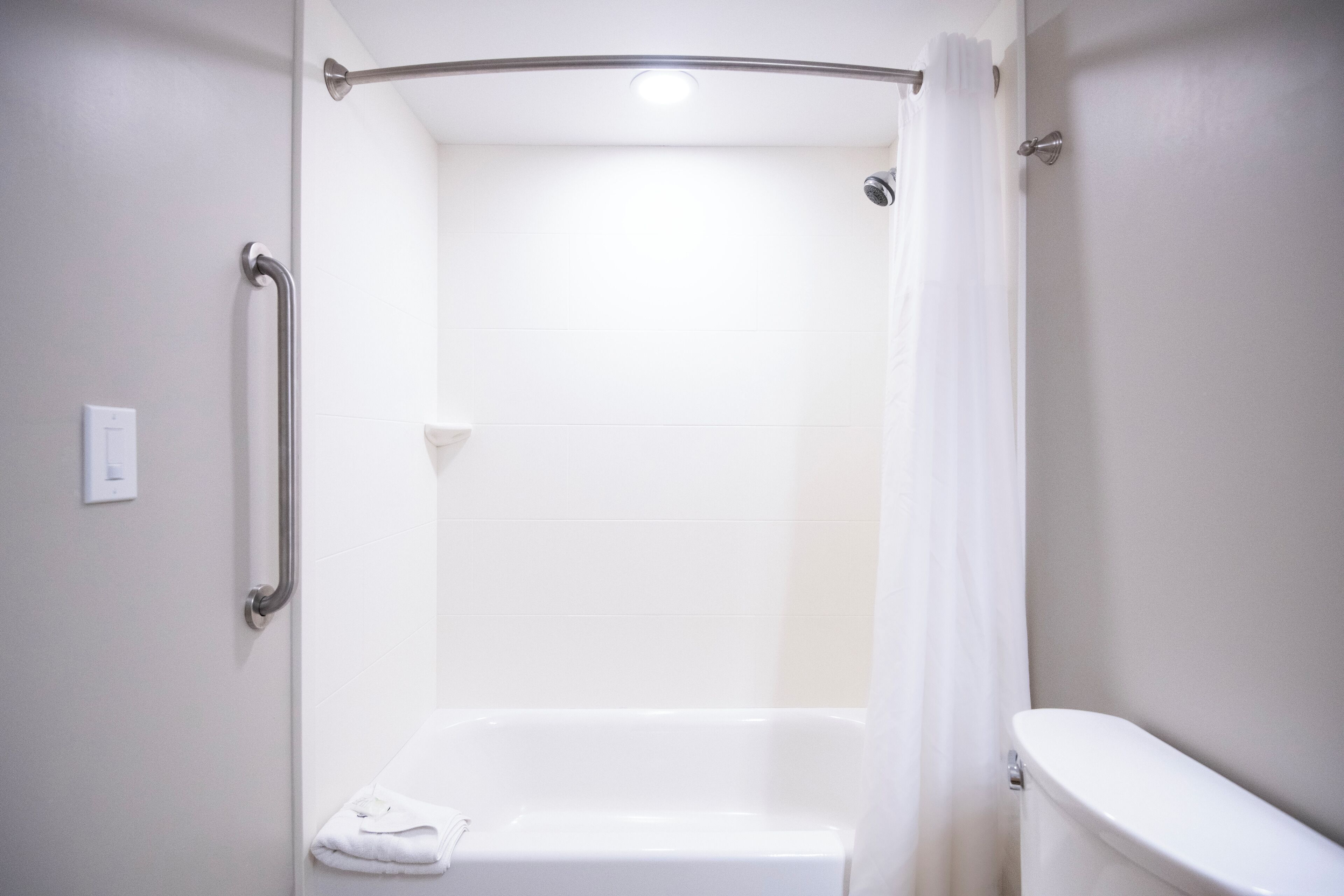 A bathroom with a white bathtub, a white toilet, and a shower curtain.