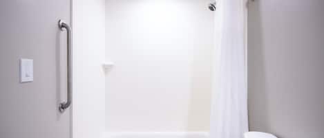 A bathroom with a white bathtub, a white toilet, and a shower curtain.