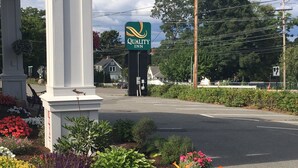 A Quality Inn sign, a road with a pedestrian crossing, and a flower garden.
