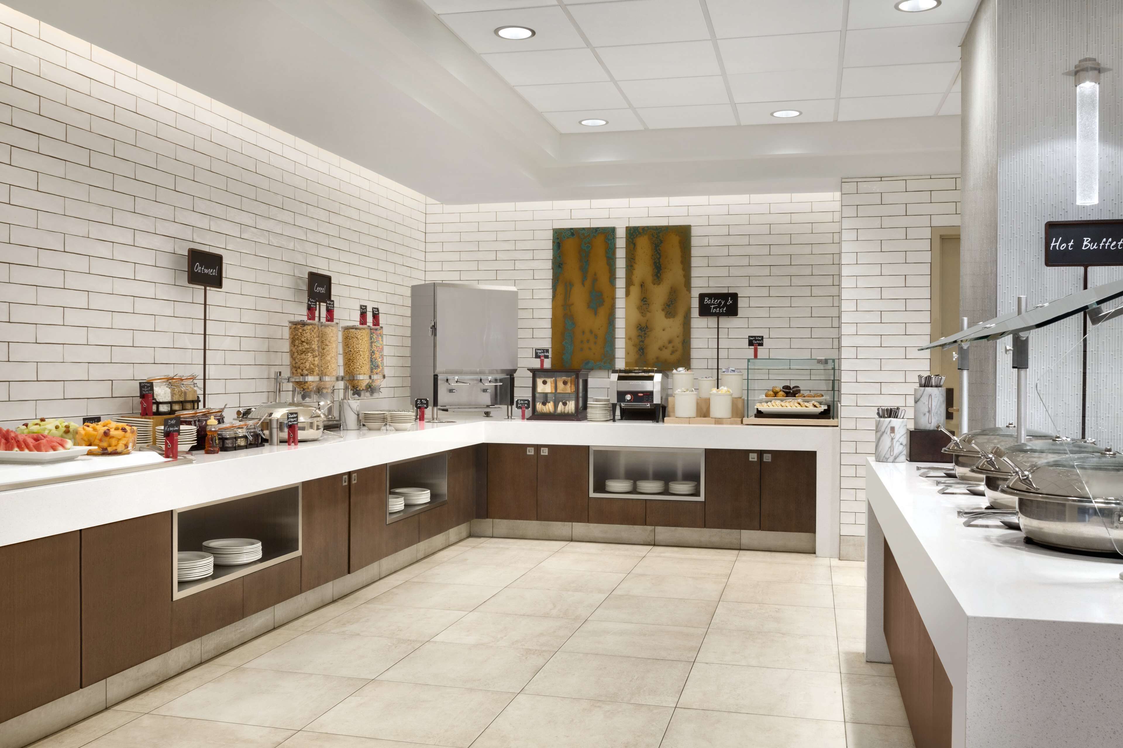 Una cocina moderna con paredes de ladrillo blanco, encimera blanca y diferentes alimentos y electrodomésticos.