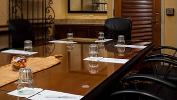 Un salón de conferencias con una larga mesa, sillas, vasos de agua y un pequeño recipiente decorativo.