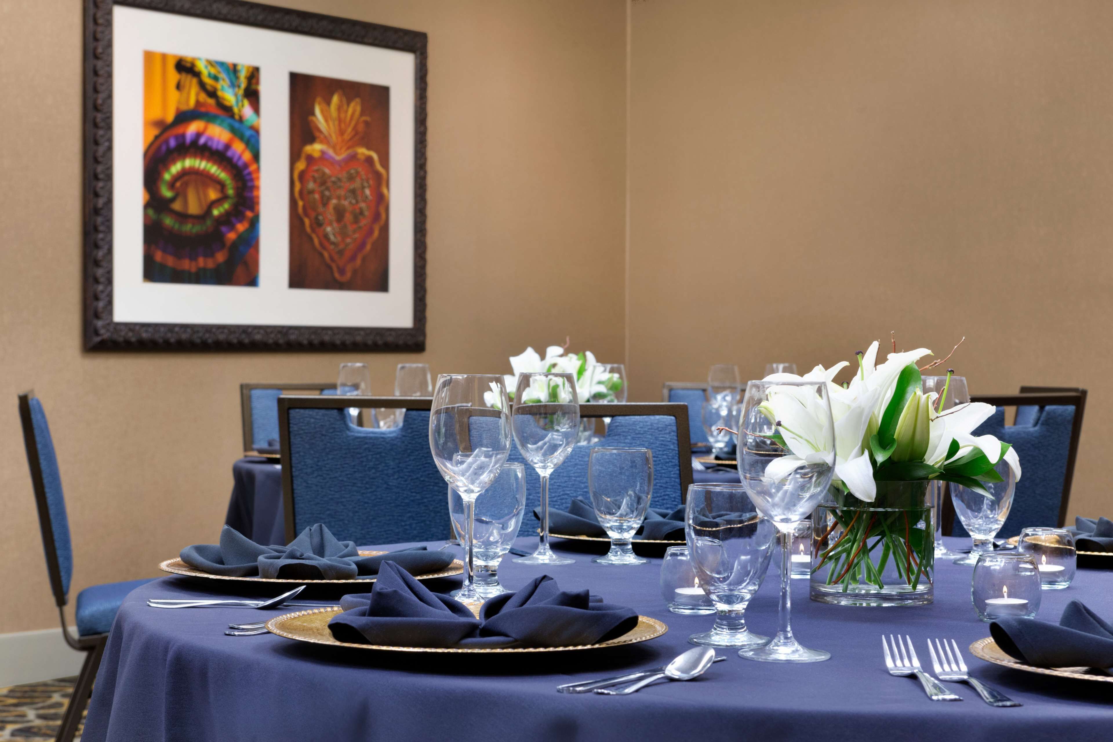 A dining table set with blue tablecloth, white napkins, and clear glassware.