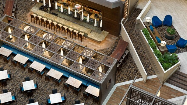 A modern bar area with seating and a staircase leading to an upper level.