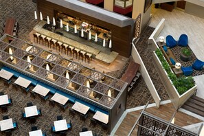 A modern bar area with seating and a staircase leading to an upper level. - Embassy Suites by Hilton San Antonio Airport (San Antonio)