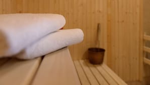 Eine Holzsauna mit einer Bank und einem kleinen Holz-Eimer.
