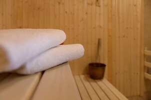 Una sauna de madera con un banco y un balde pequeño de madera.