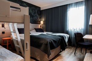 Una camera d'albergo con un letto a castello, una scrivania, una sedia, una lampada e vista sull'esterno.