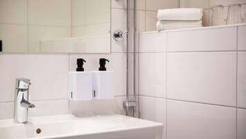 Un baño con lavamanos blanco, espejo y cabina de ducha de vidrio.