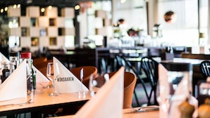 Ein Restaurantinnenraum mit gedeckten Tischen, einschließlich eines Menüständers mit der Aufschrift 'KÖKSBAREN'.