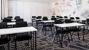 Ein Konferenzraum mit Tischen, Stühlen, einem Projektor und einer Wandmalerei mit einer Weltkarte.