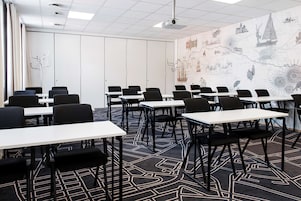 Un salón de conferencias con mesas y sillas, un proyector y un mural de un mapa en la pared.