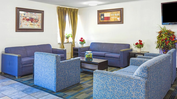 A room with a blue sofa set, patterned armchairs, a coffee table, and two flower vases.