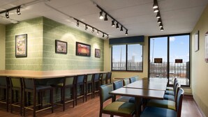 Une salle de conférence avec une longue table et des chaises, des tableaux accrochés au mur et de grandes fenêtres.