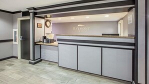 A reception area with a Baymont Inn & Suites sign, a reception desk, and a clock on the wall. - Americas Best Value Inn Canton (Canton)