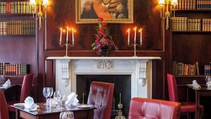 Une salle à manger élégante, dotée d’une cheminée, de bibliothèques et de fauteuils en cuir rouge.
