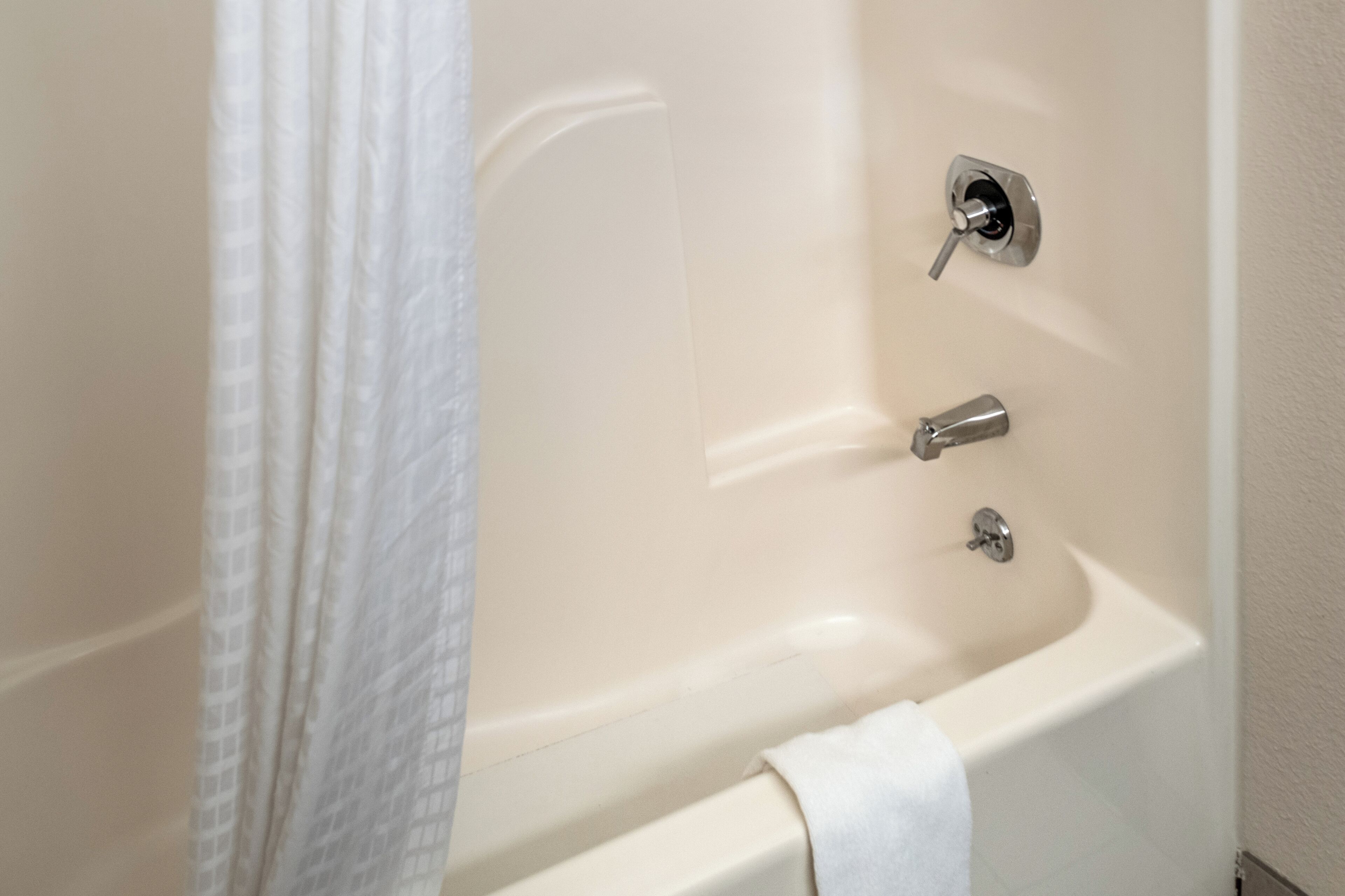 A bathtub with a shower curtain, a faucet, and a towel.