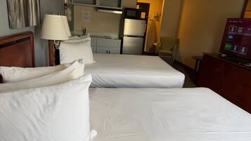Habitación de hotel con dos camas, un escritorio, una silla, un televisor y una kitchenette.