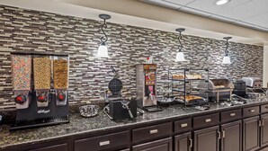 A breakfast bar with various food dispensers, waffle maker, and a coffee station. - Rodeway Inn (Barboursville)