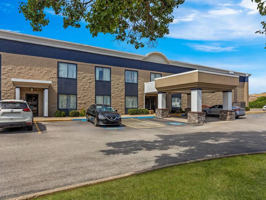 Un hotel con parcheggio, diverse auto e un cielo azzurro.
