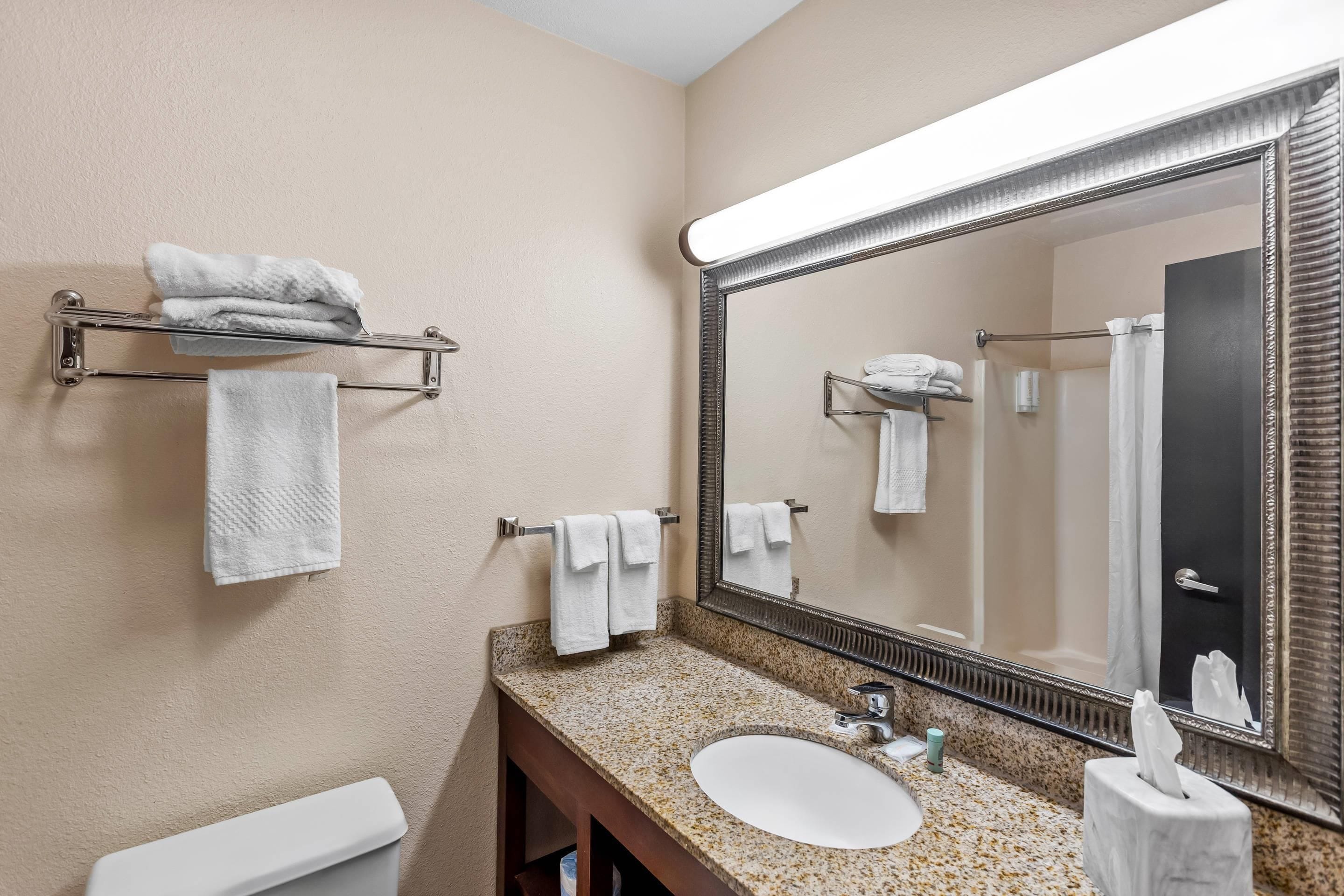 A bathroom with a sink, mirror, towel rack, and toilet.