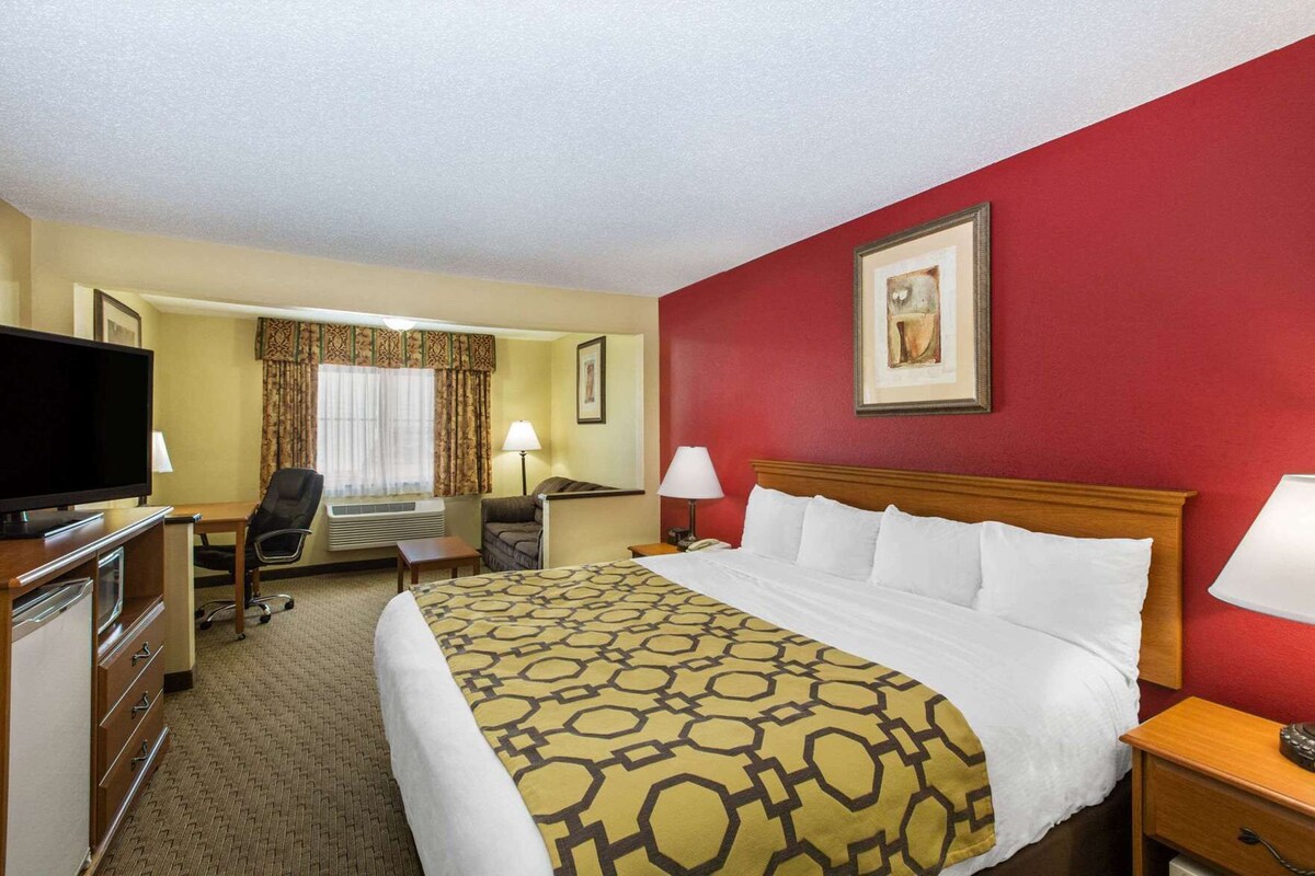 A hotel room with a bed, a desk, a television, a chair, and a lamp.