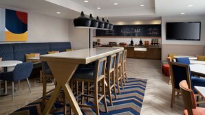 Una cocina moderna con comedor, que cuenta con una isla grande, taburetes de bar y un televisor montado en la pared.