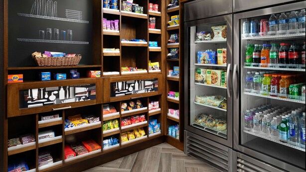 Una despensa bien organizada, con estantes llenos de refrigerios, bebidas y artículos del hogar.