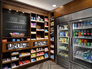 Una despensa bien organizada, con estantes llenos de refrigerios, bebidas y artículos del hogar.