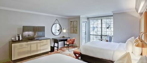 A hotel room with two beds, a desk with a chair, a TV, and a large window.