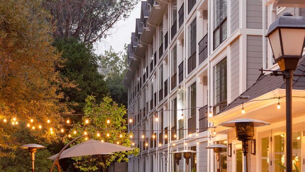 A hotel courtyard with outdoor seating, string lights, and a well-maintained garden. - The Inn at Saratoga, Tapestry Collection by Hilton (Saratoga)