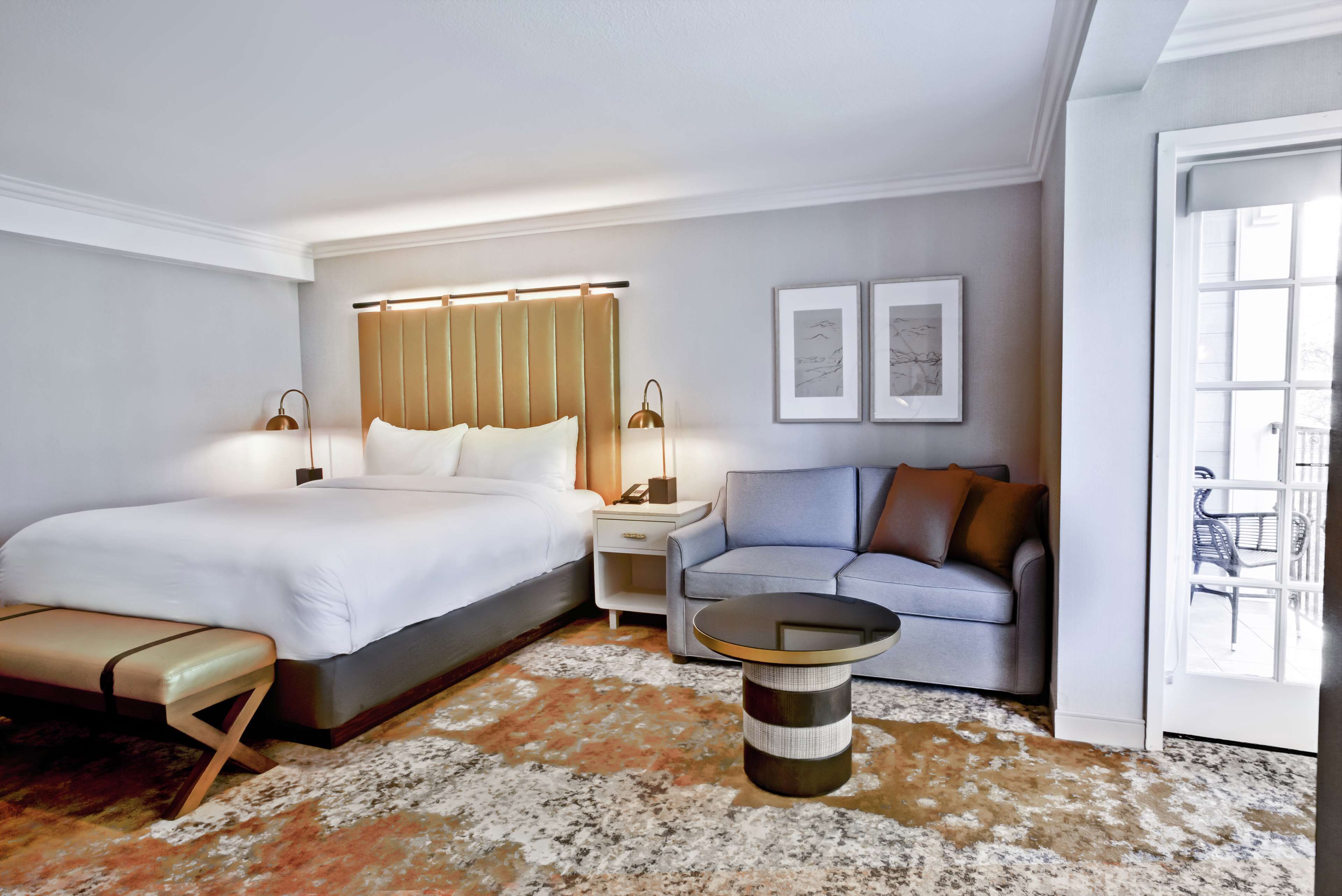 Een hotelkamer met een groot bed, een bank, een klein tafeltje en een nachtkastje.