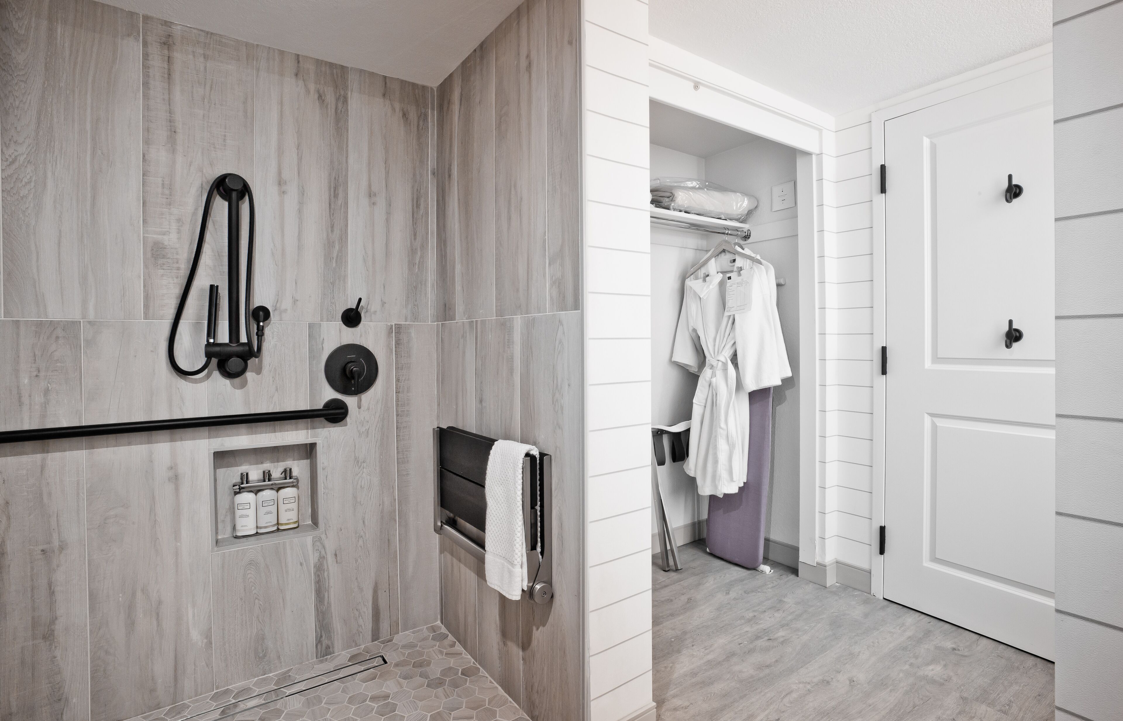 A modern bathroom with a shower, towel rack, and storage cabinets.