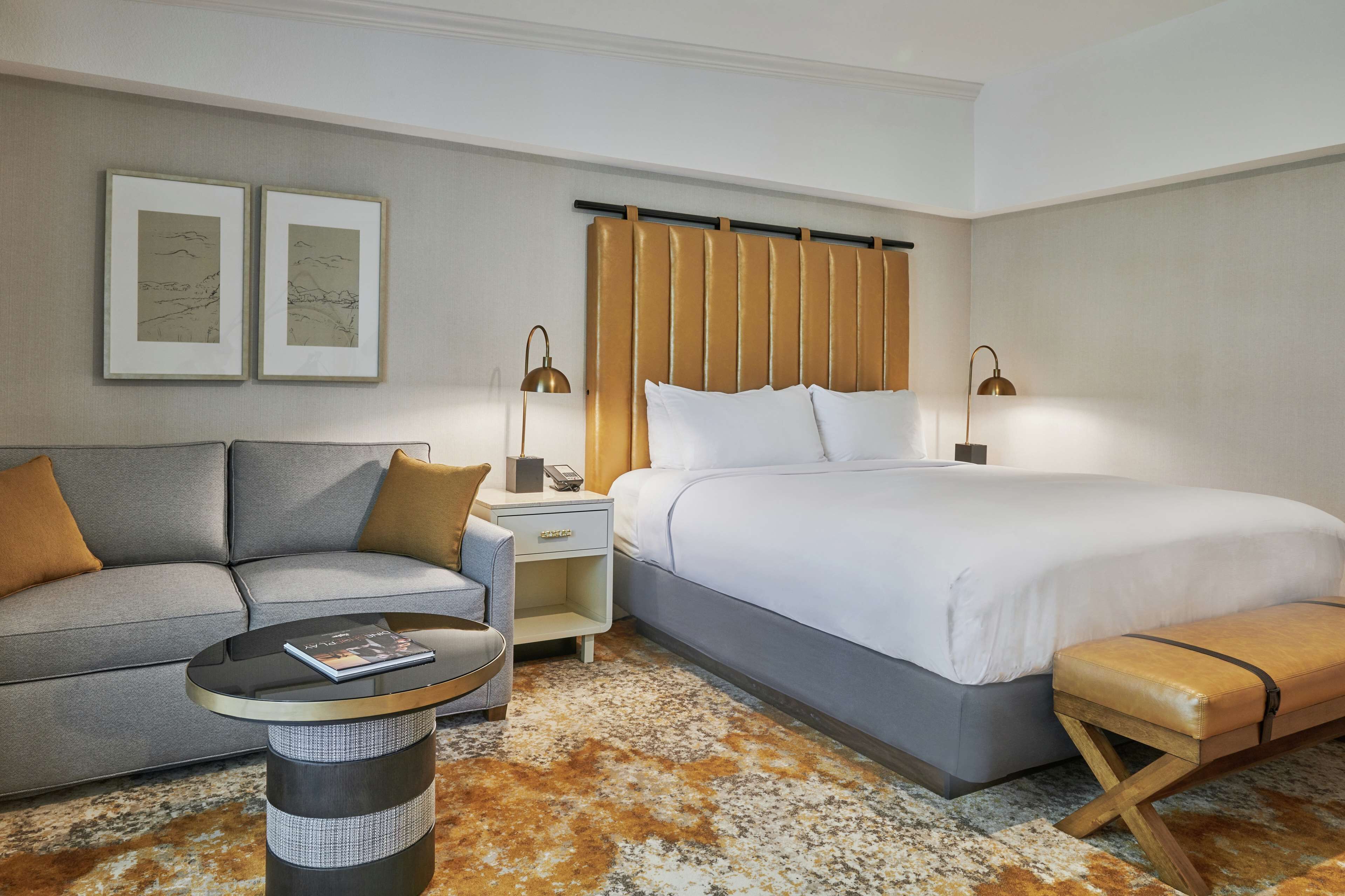 Una habitación de hotel con una cama, un sofá, una mesita y un banco.