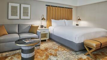 Una habitación de hotel con una cama, un sofá, una mesita y un banco.