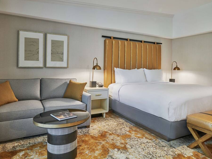 Una habitación de hotel con una cama, un sofá, una mesita y un banco.