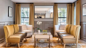 A modern living room with two leather armchairs, a central coffee table, and a large window with curtains. - The Inn at Saratoga, Tapestry Collection by Hilton (Saratoga)