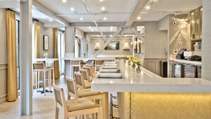 A modern bar area with a long counter, multiple bar stools, and a seating area with tables and chairs. - The Inn at Saratoga, Tapestry Collection by Hilton (Saratoga)