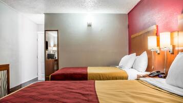 Une chambre d’hôtel avec deux lits, une tête de lit en bois, des lampes de chevet, un téléphone et un miroir.