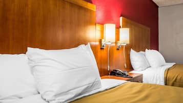 A hotel room with two beds, wooden headboard, bedside lamps, a telephone, and a nightstand.